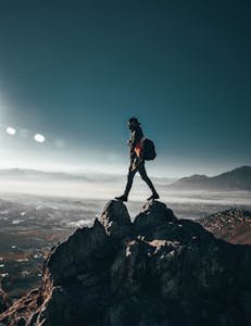 A lone hiker conquering rocky peaks in Nawur, Afghanistan under a clear sky.